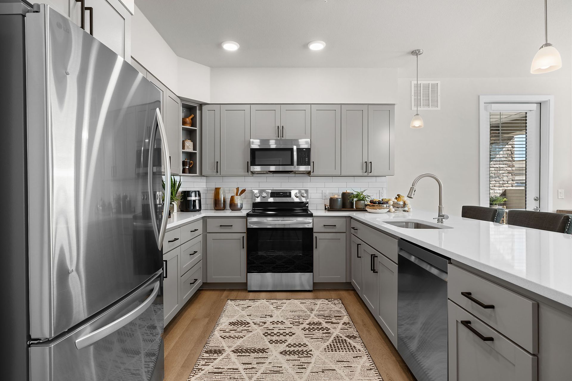 Modern kitchen with gray cabinets, stainless steel appliances, and a white countertop at Marq Bronco Butte.
