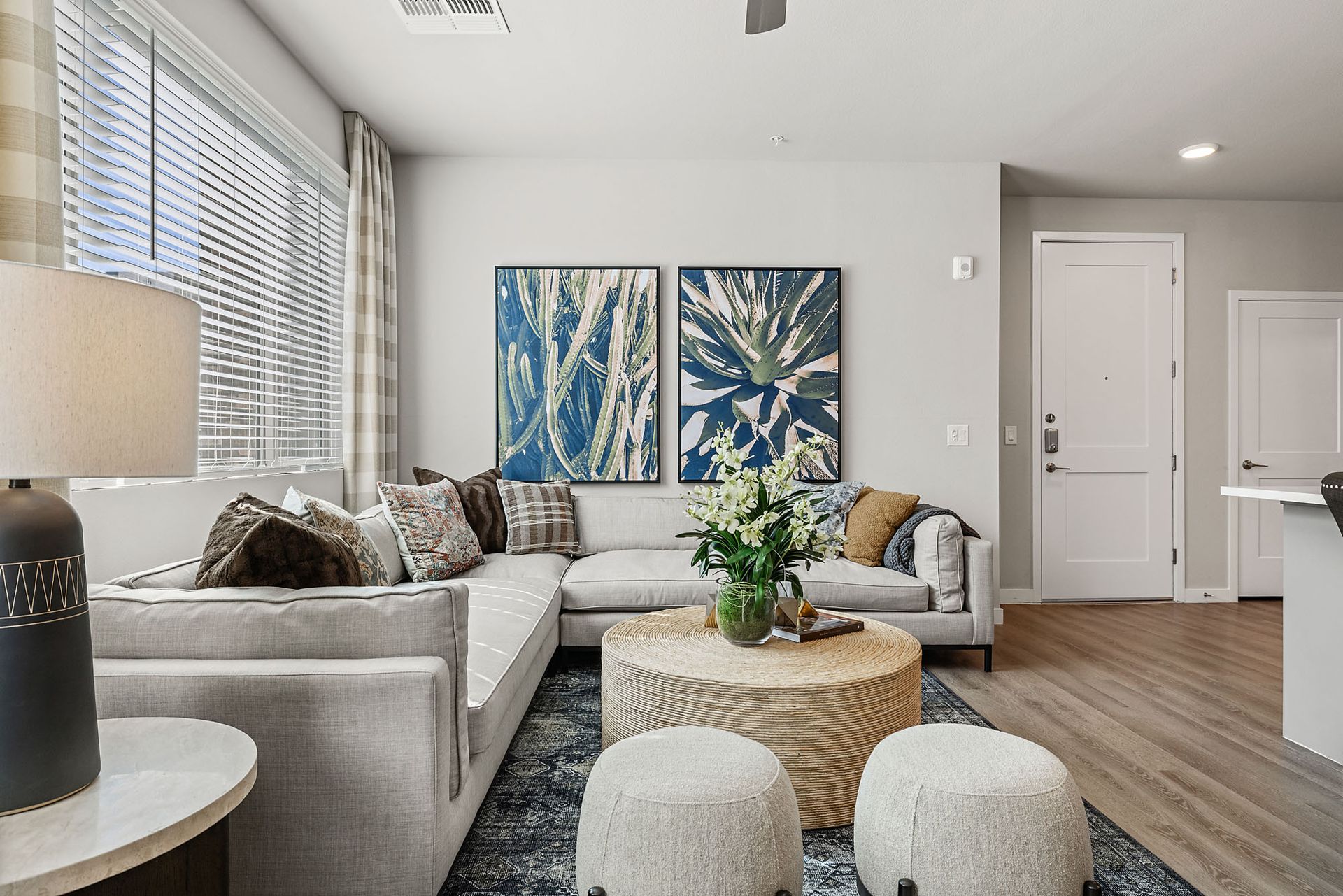 Living room with gray sectional, round coffee table, blue art, and neutral decor at Marq Bronco Butte, offers  apartments in North Phoenix, AZ.