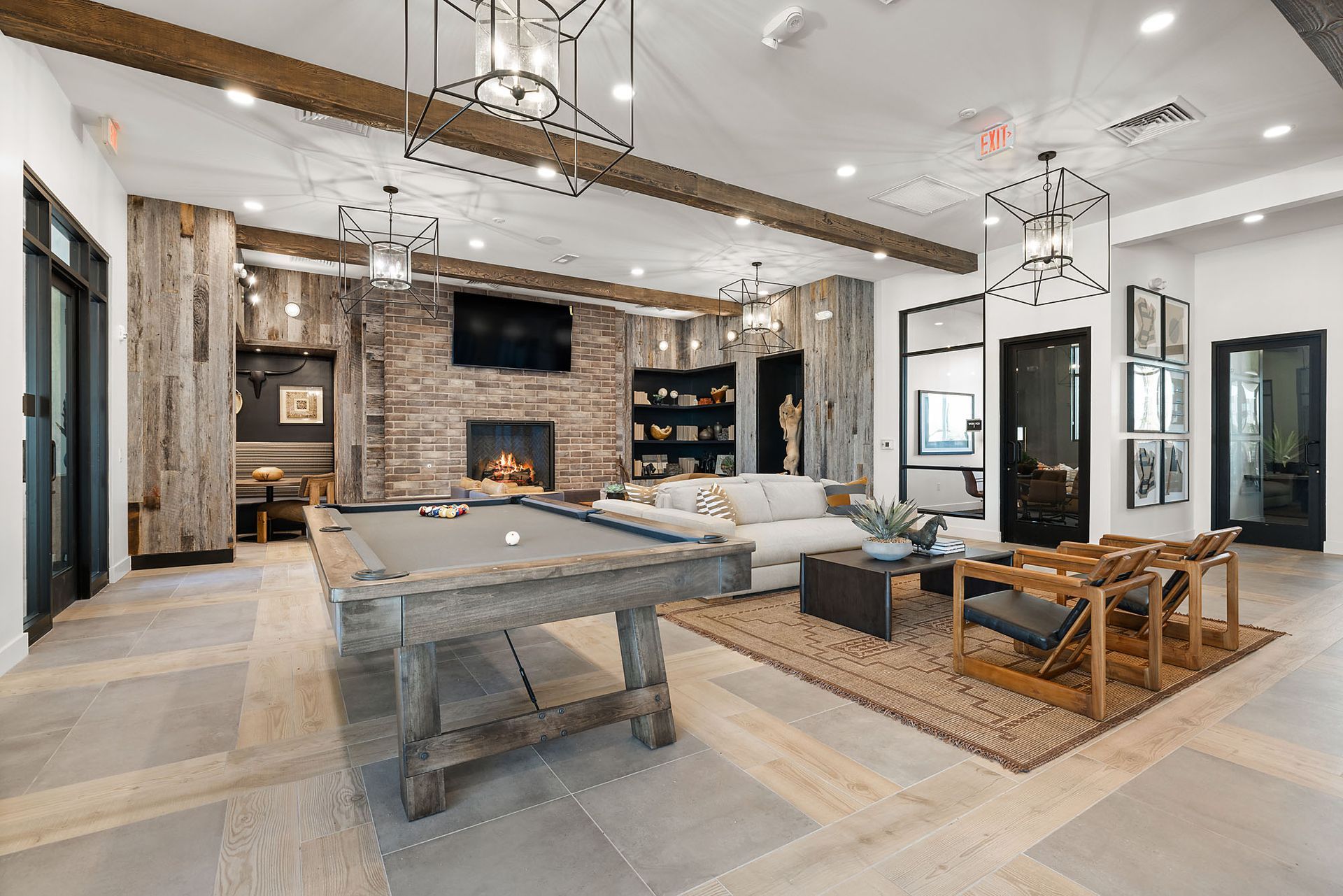 Lounge with a pool table, fireplace, seating, and wooden beams. Neutral colors, modern rustic style.