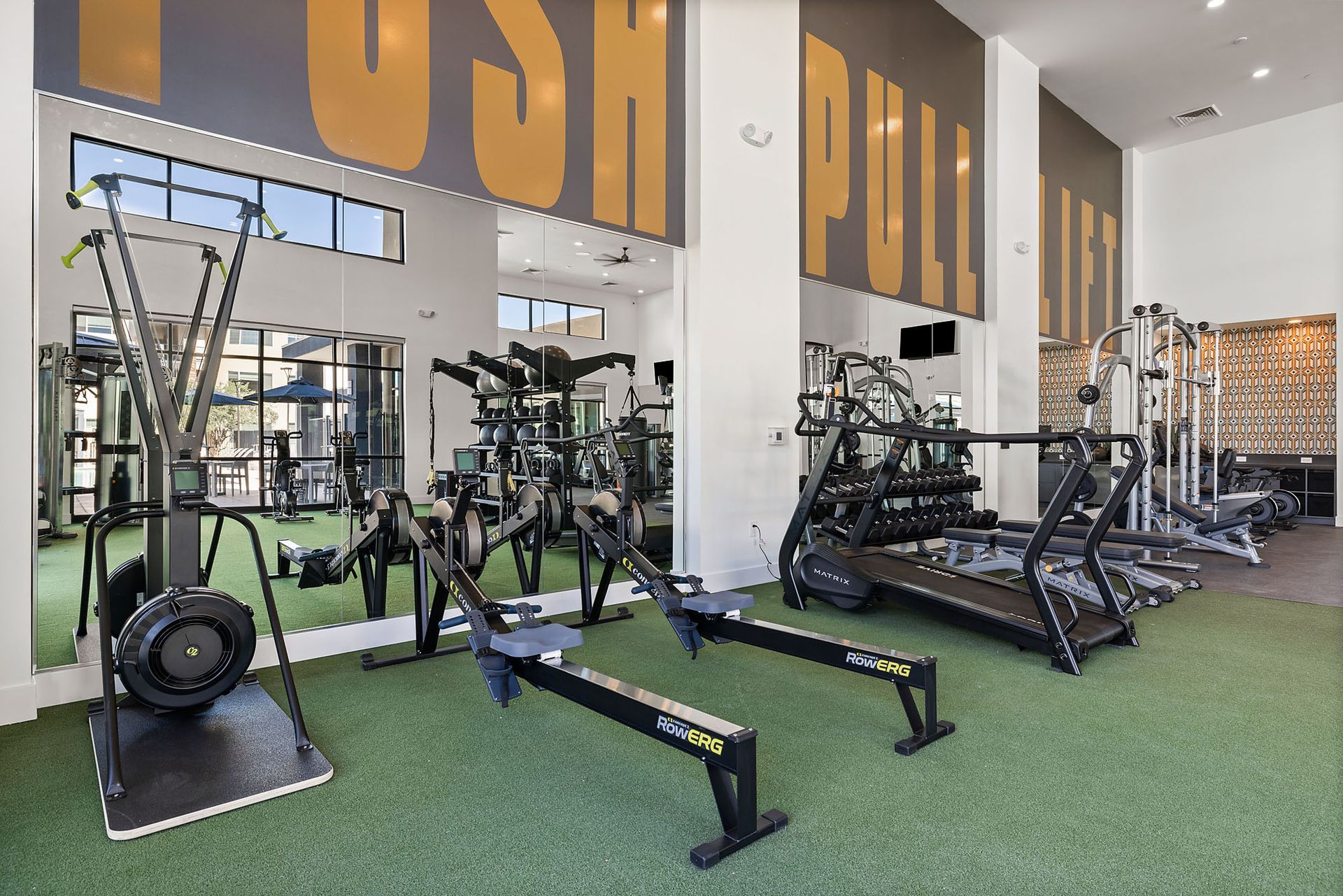 Gym interior with exercise machines, mirrors, and 