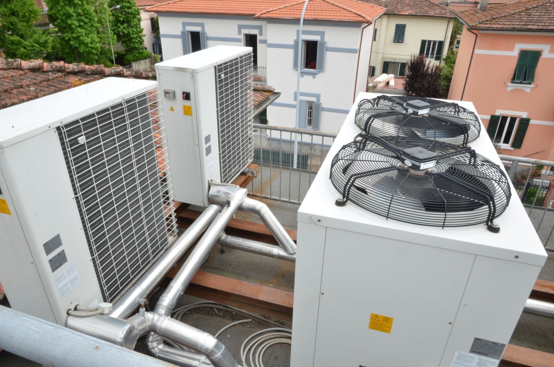 Unità e condotti HVAC esterni su una terrazza sul tetto adiacente agli edifici vicini.