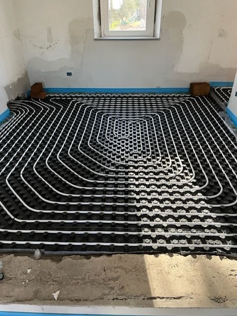 Tubi per riscaldamento a pavimento radiante installati su un pavimento non rifinito sotto una finestra