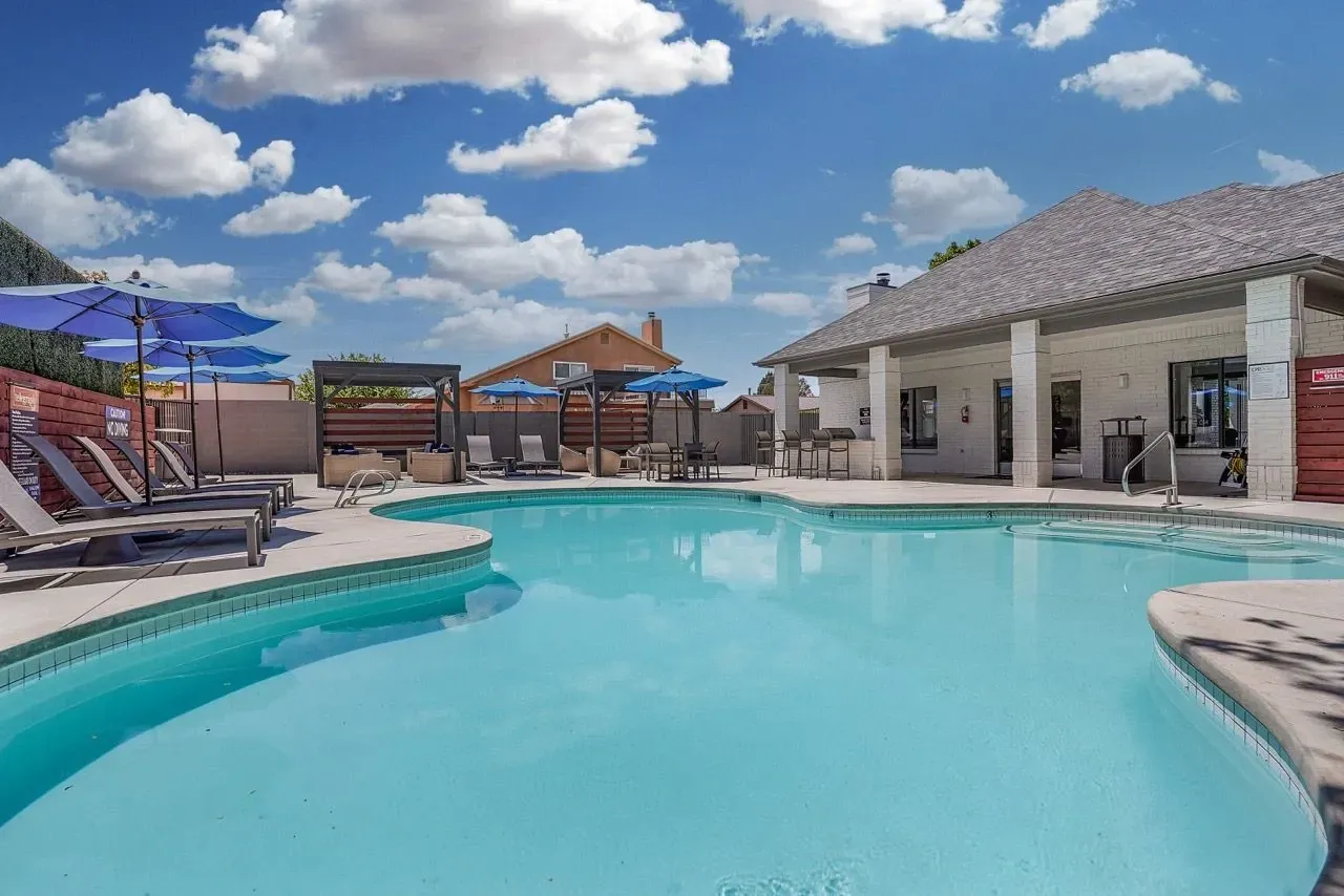 Resort-style swimming pool with lounge chairs and umbrellas.