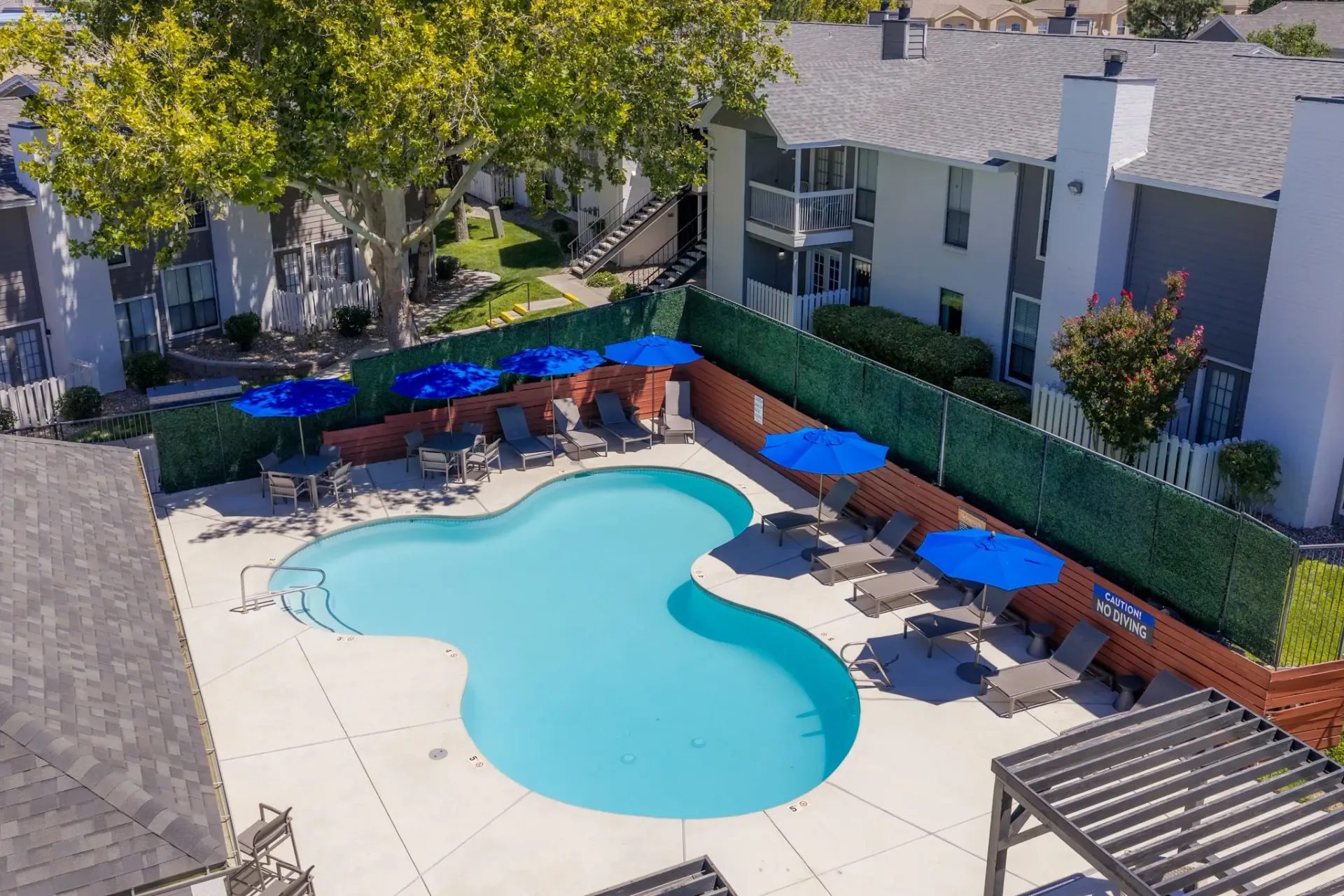 Outdoor swimming pool with lounge chairs and blue umbrellas.