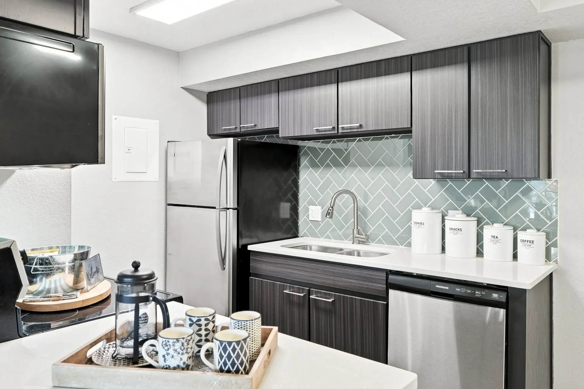 Modern kitchen with stainless steel appliances, dark wood cabinets, and a tiled backsplash.