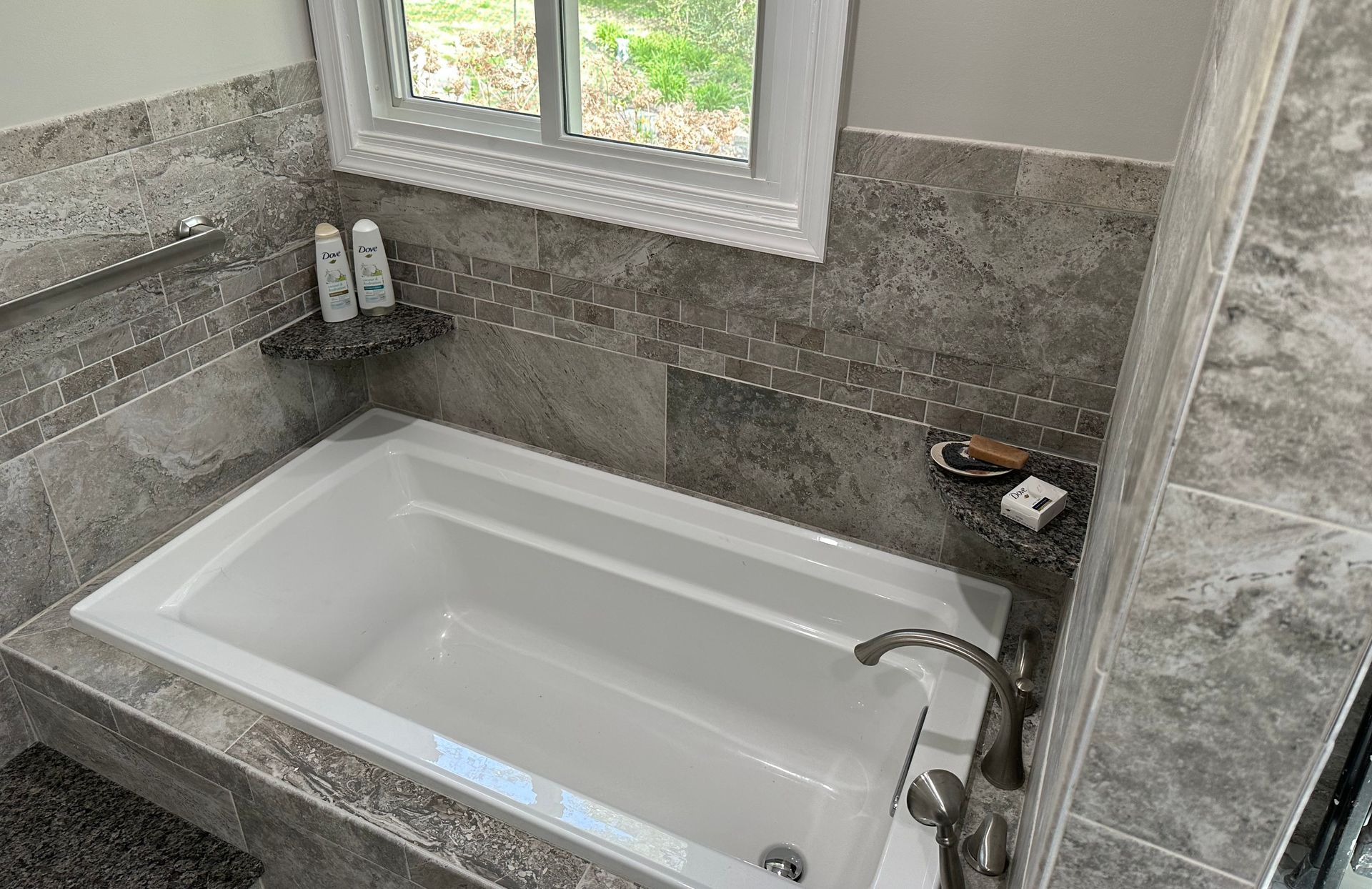 A bathtub in a bathroom next to a window.