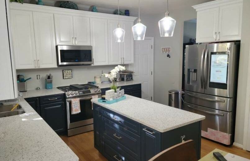 A kitchen with white cabinets , stainless steel appliances , and a large island.