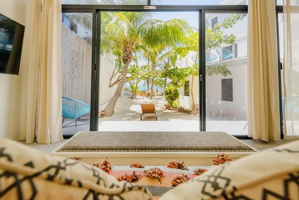 Room with a large window overlooking a tropical yard with a beach chair.