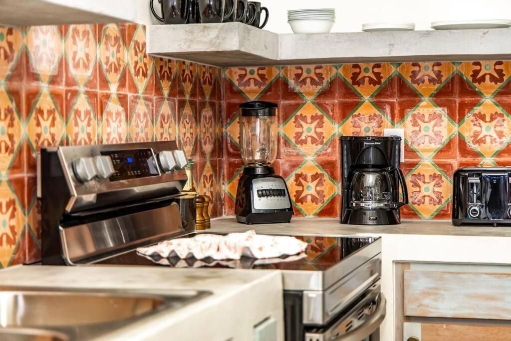Kitchen with stove, blender, coffee maker, and patterned backsplash.