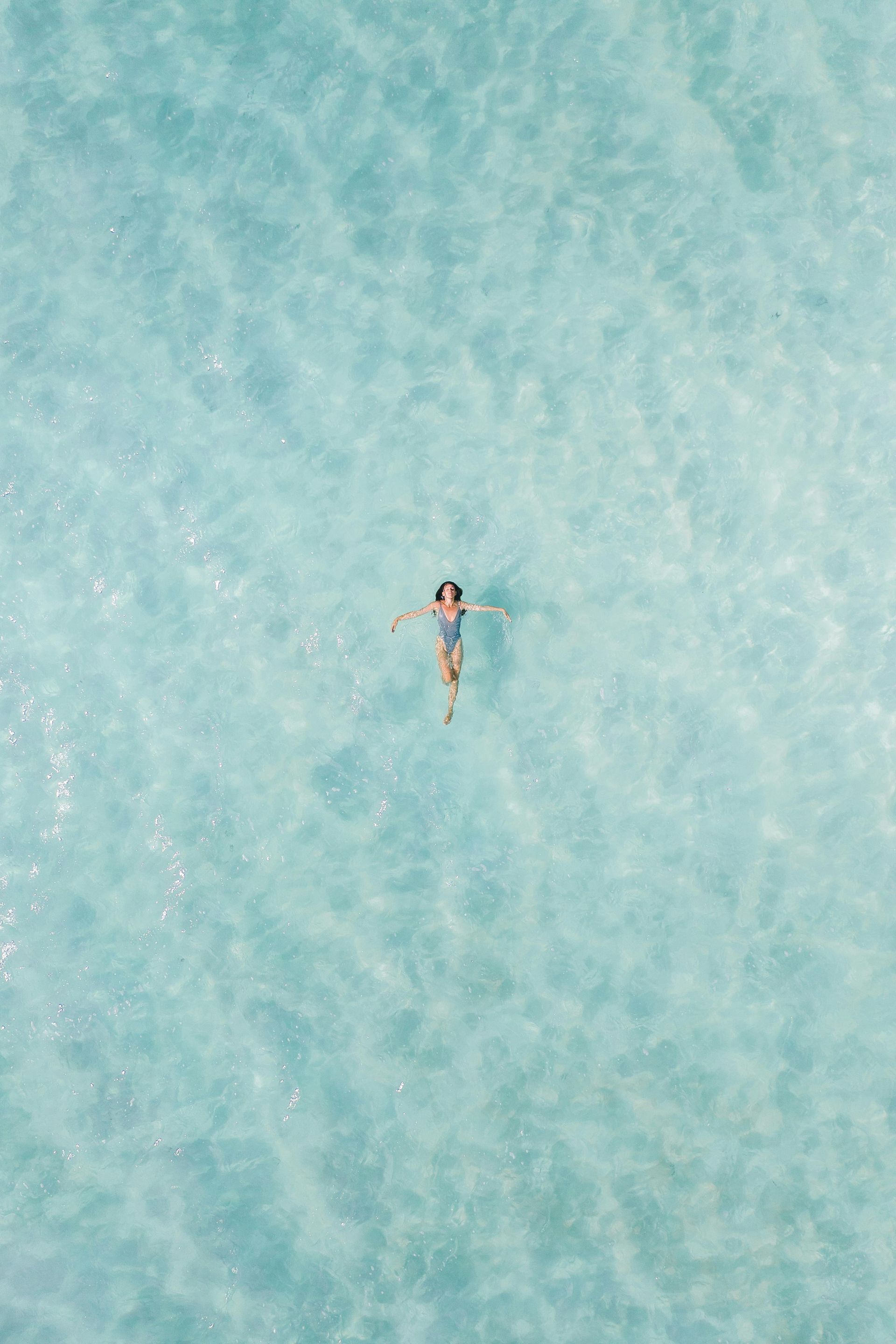 Person floating on back in bright turquoise water.
