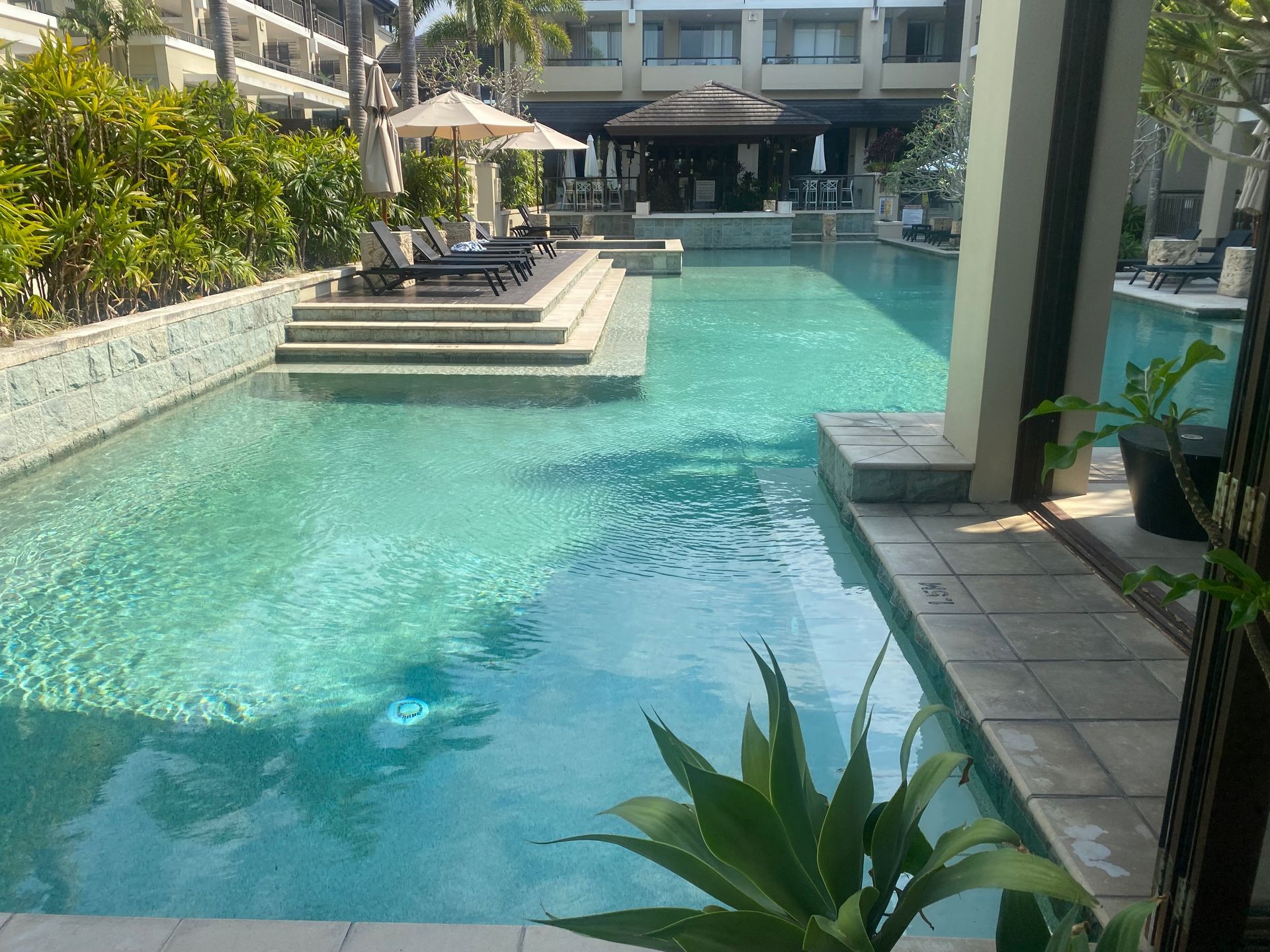 A Large Indoor Swimming Pool With Chairs and Umbrellas Around It — Tweed Coast Pool Care in South Murwillumbah, NSW