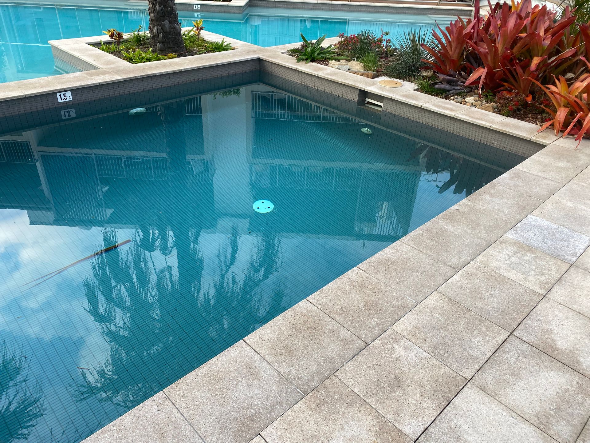 A Bottle of Chemicals is Sitting on the Edge of a Swimming Pool — Tweed Coast Pool Care in South Murwillumbah, NSW