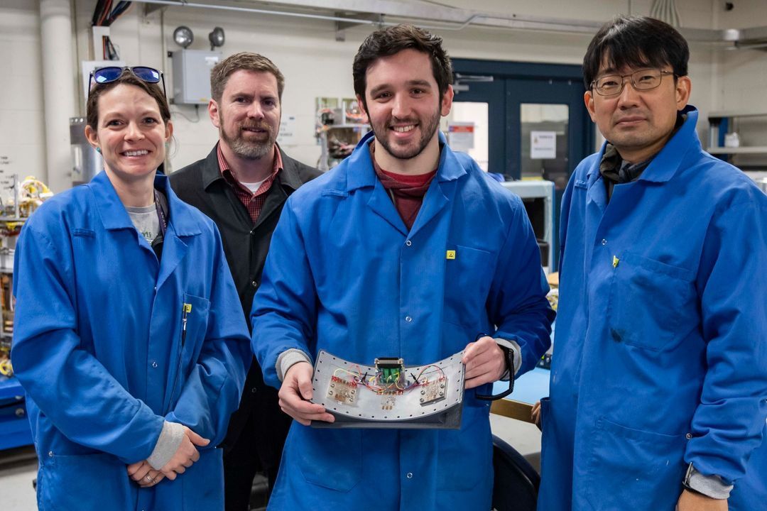 A group of people wearing blue lab coats are posing for a picture.