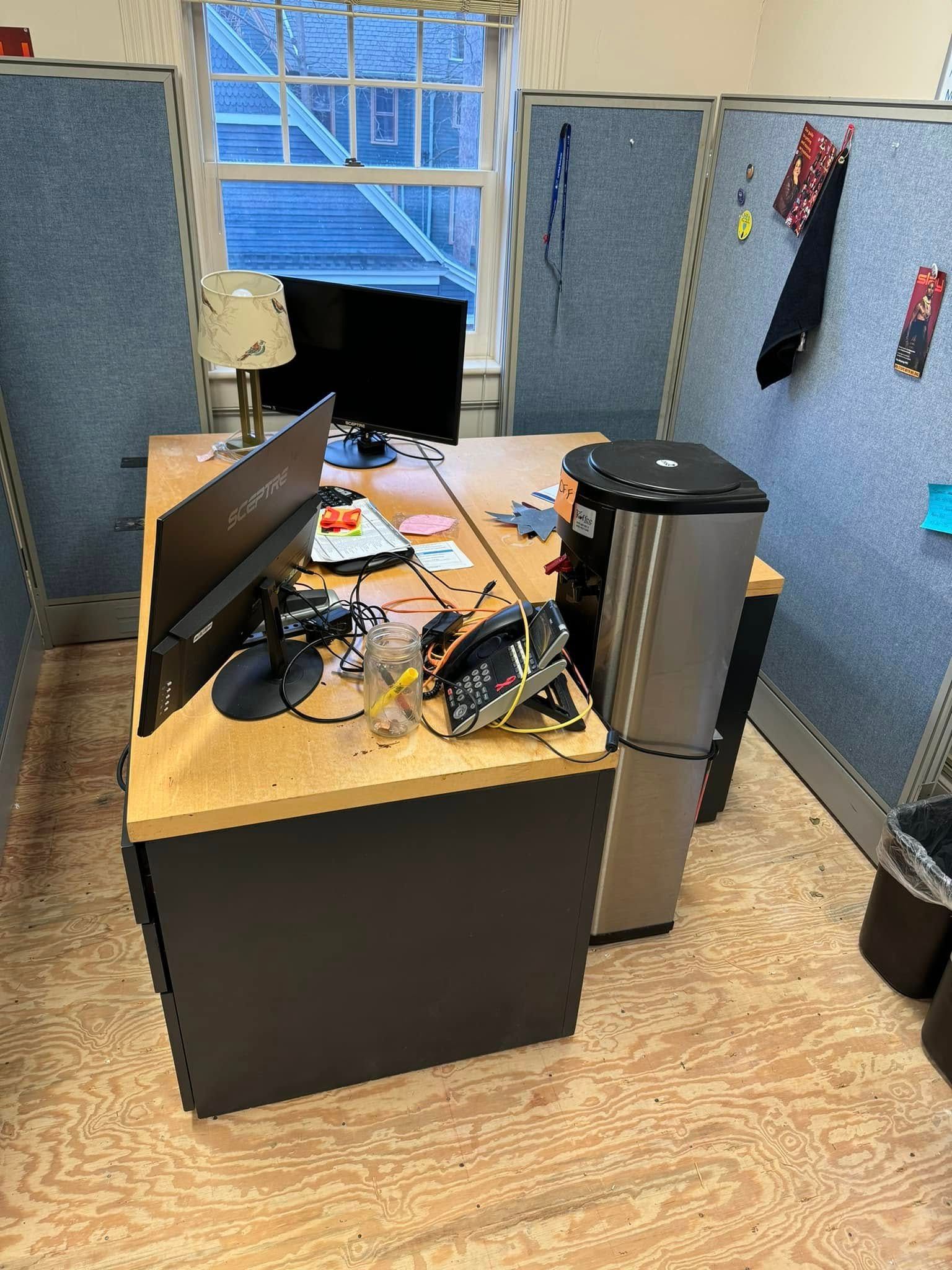 Office desk with computer, water cooler, and window.