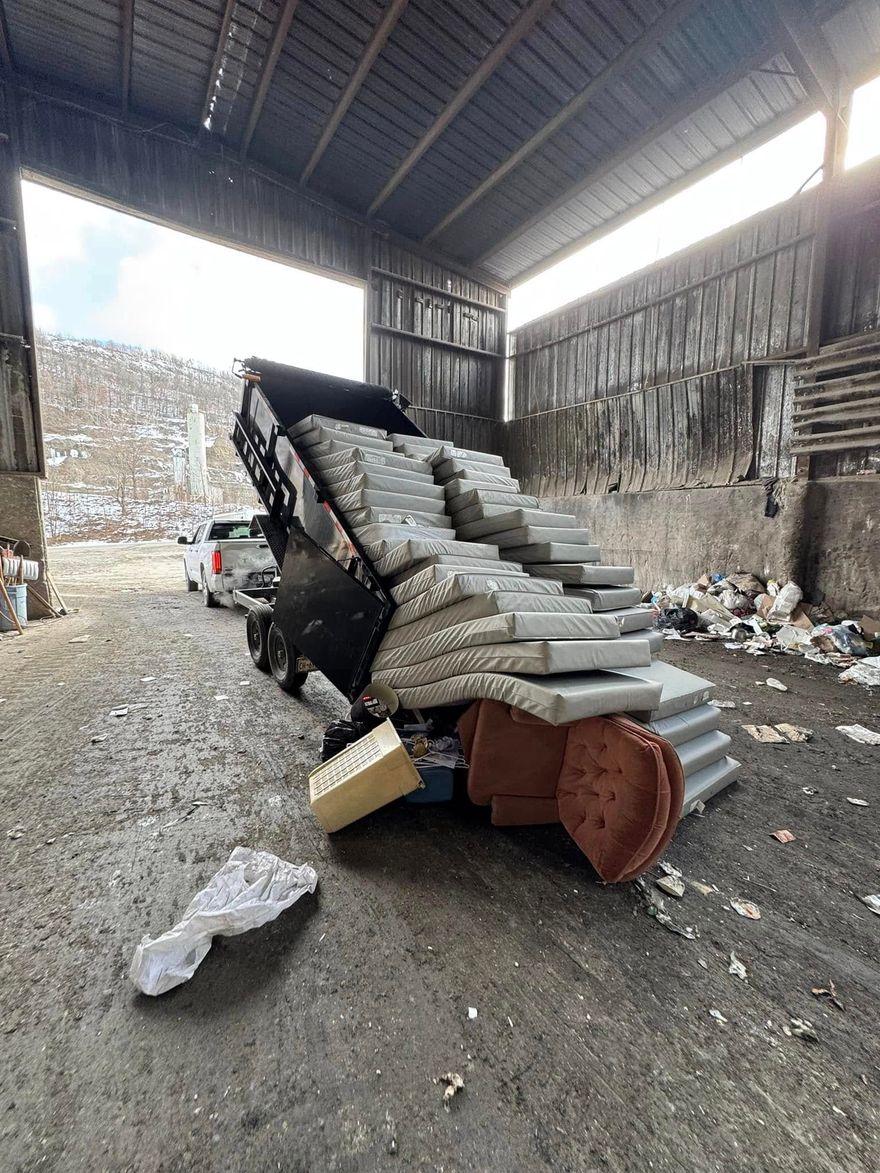 Dump truck unloading gray concrete blocks at a waste facility.