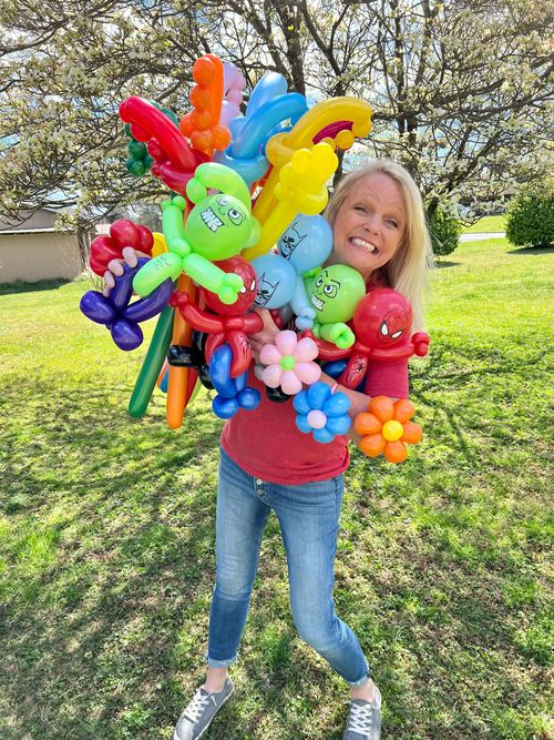 A woman is holding a bunch of balloons in her hands.