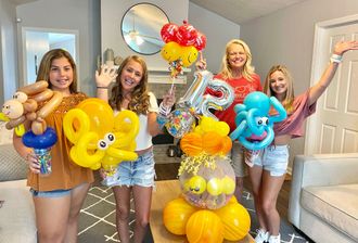 A group of women are holding balloons in a living room.
