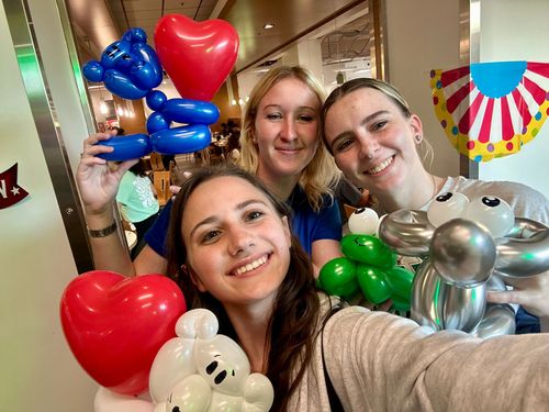 Three women are posing for a picture with balloons.