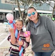 A woman and a child are posing for a picture with balloons.