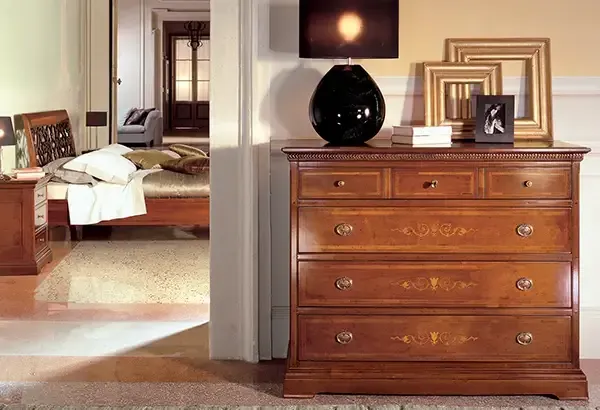 Una cassettiera di legno in una camera da letto accanto a un letto