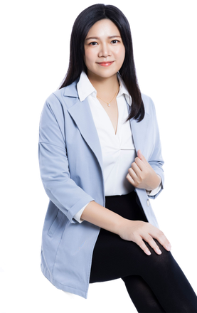 身穿藍色西裝外套、白色襯衫和黑色褲子的詠華地政士事務所所長－鄭秀慧女士，面帶微笑，坐著面對鏡頭。