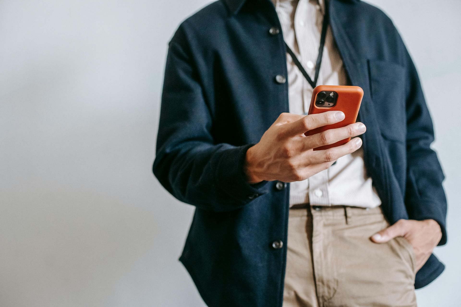 A man in a jacket is holding a cell phone in his hand.