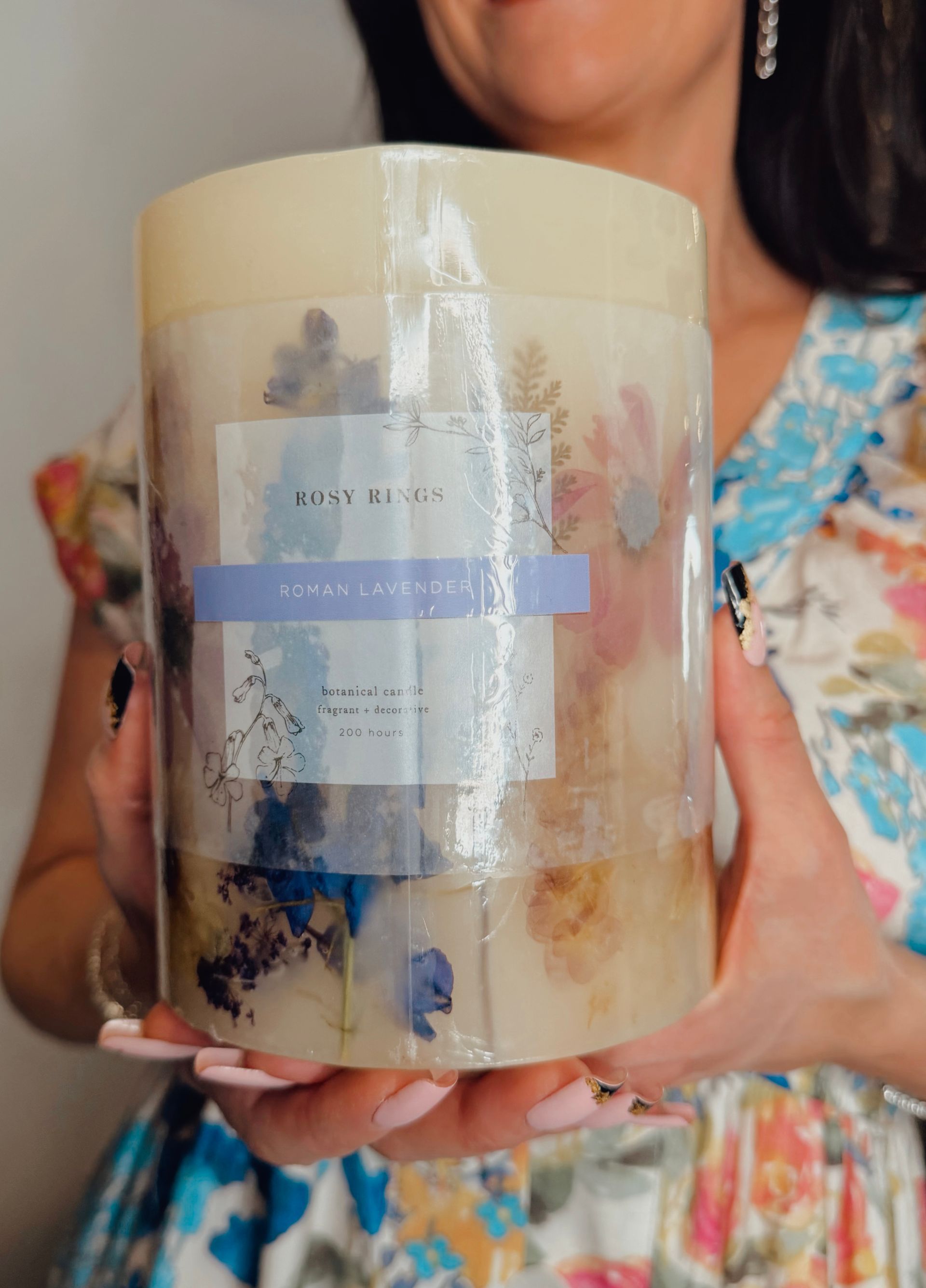 Person holding a tall beige gift box with a clear window and blue ribbon.