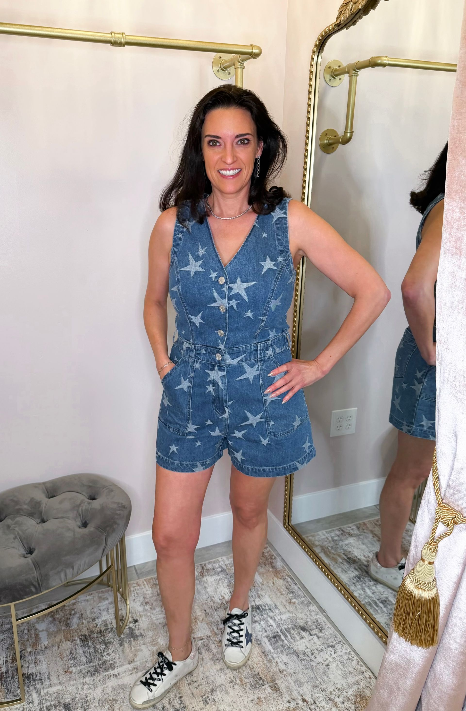 Person posing in a blue star-patterned romper and sneakers in front of a mirror.