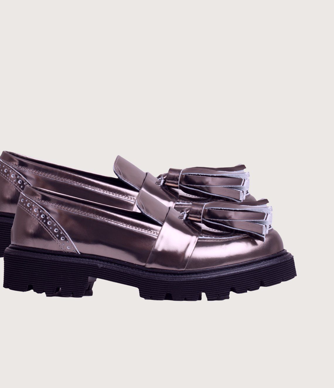 A pair of metallic loafers with tassels on a white background.