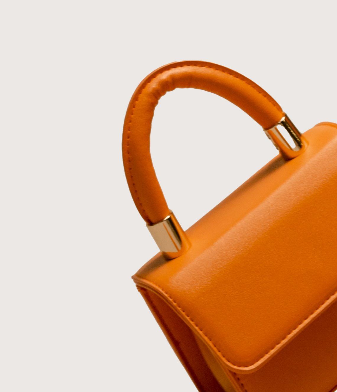 A small orange purse with a gold handle on a white background.