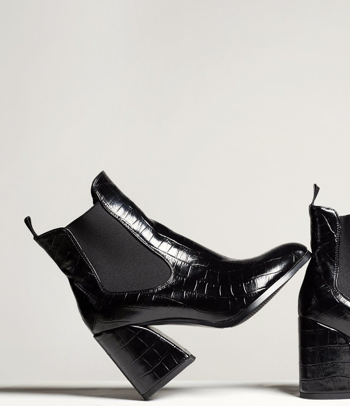 A pair of black ankle boots with a high heel on a white background.