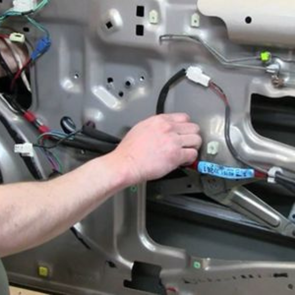 Person working inside a car door panel with exposed wiring and mechanisms