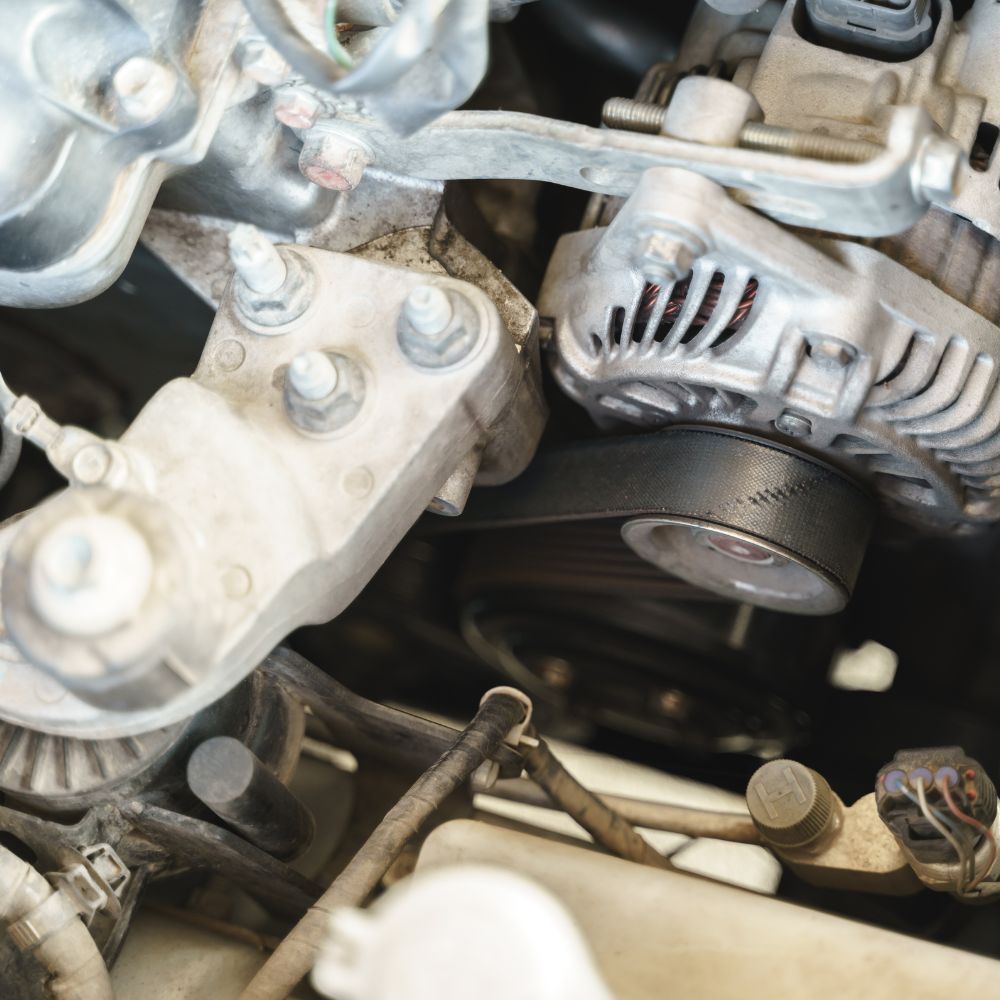 Close-up of a car engine bay showing an alternator and metal components.