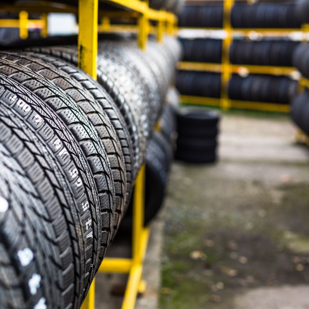 Rows of black tires stacked on yellow racks in a warehouse or tire shop
