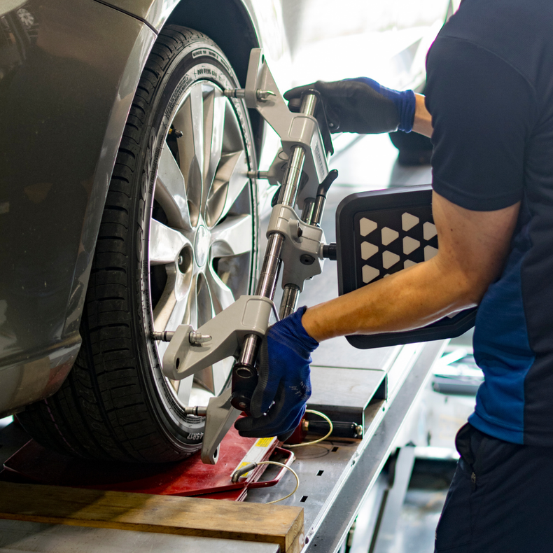Technician using wheel alignment machine on a car tire in an auto shop