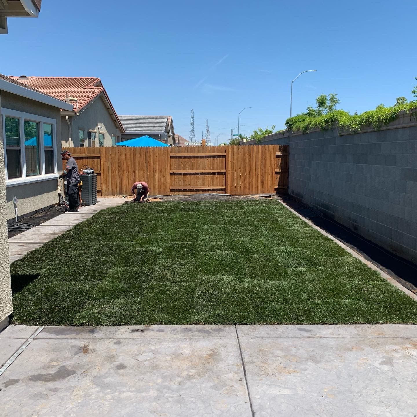 A backyard with a large lawn and a wooden fence.