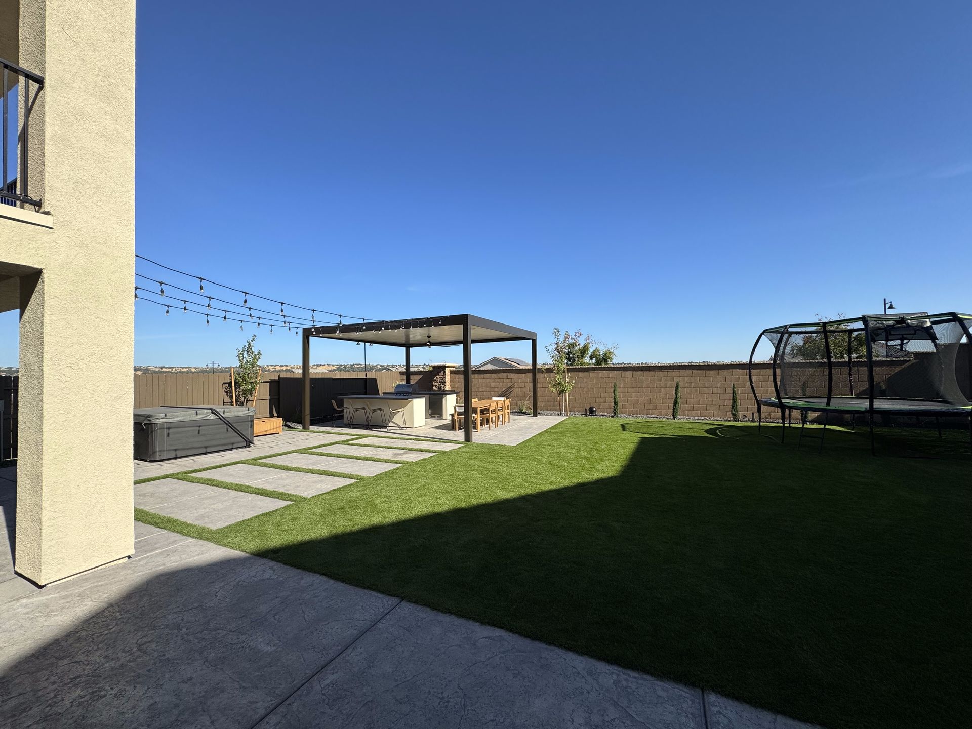 The backyard of a house with a trampoline and a gazebo