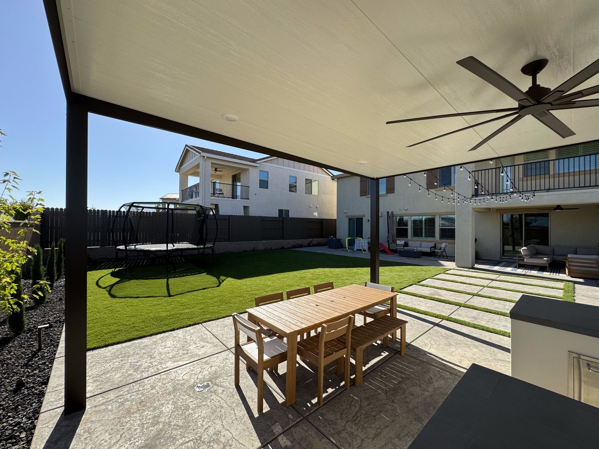 A patio with a table and chairs under a canopy with a ceiling fan.