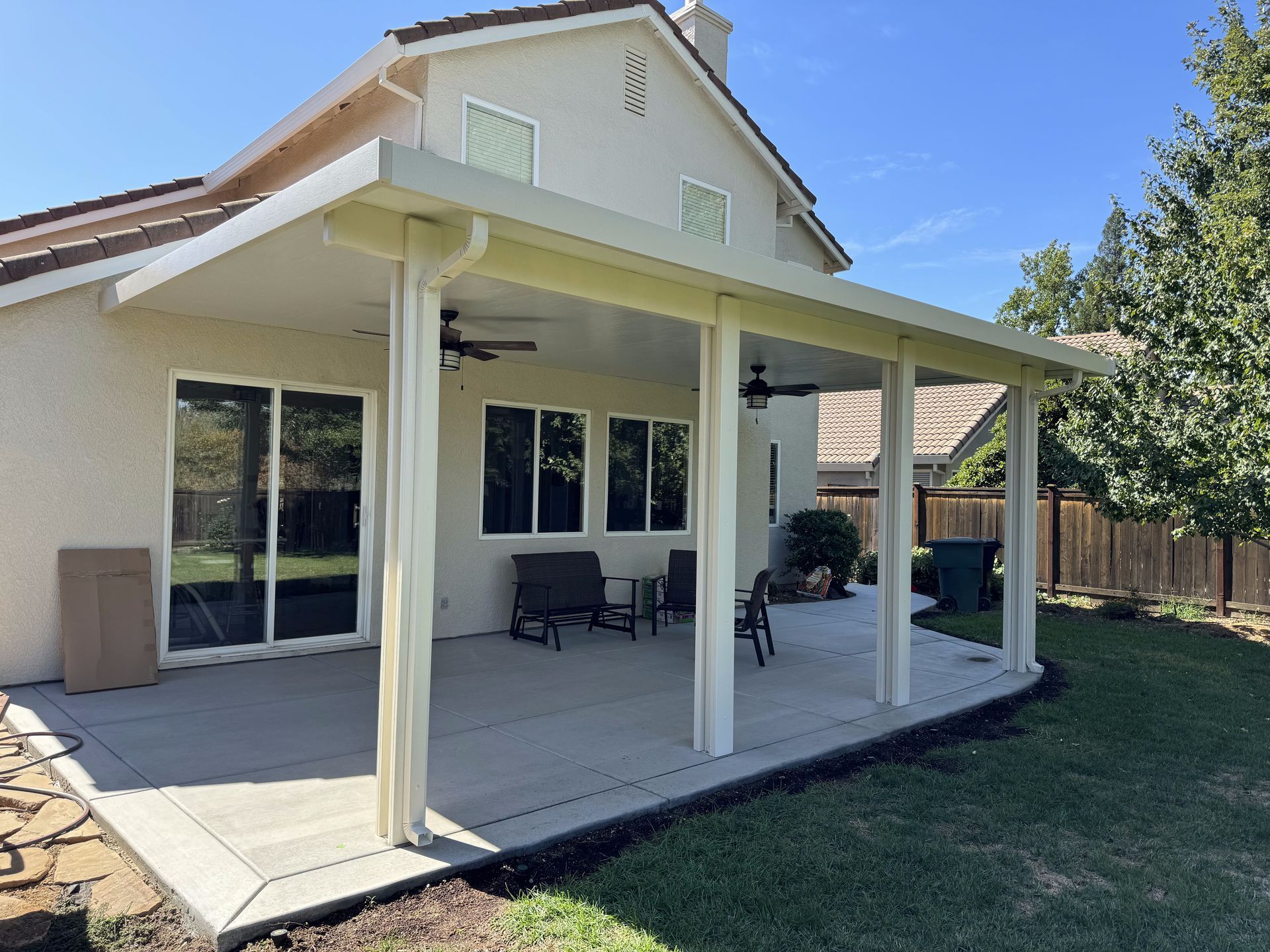 A white house with a covered patio in the backyard.