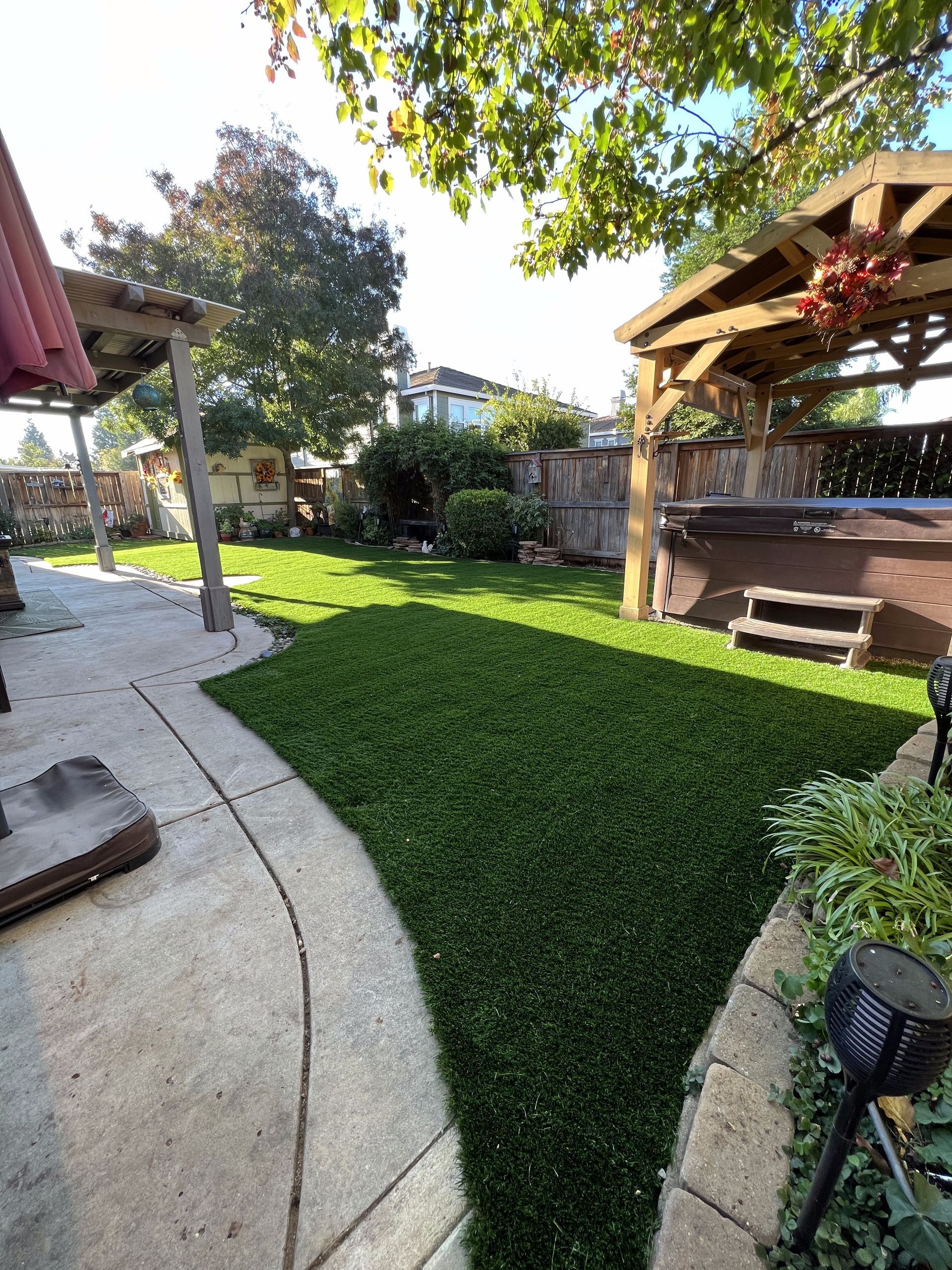 A backyard with a hot tub and a gazebo.