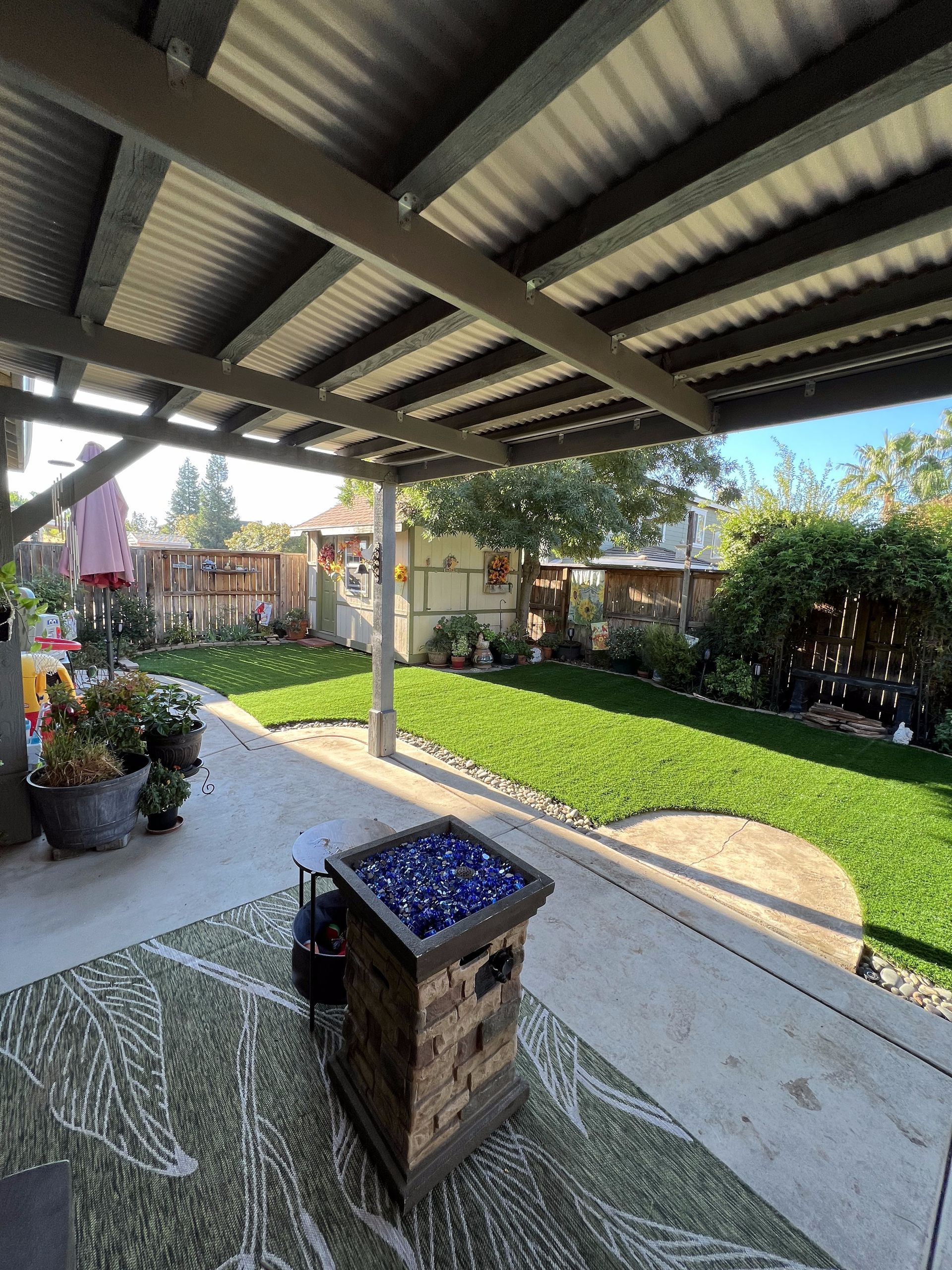 A patio with a fire pit and a rug under a covered patio.