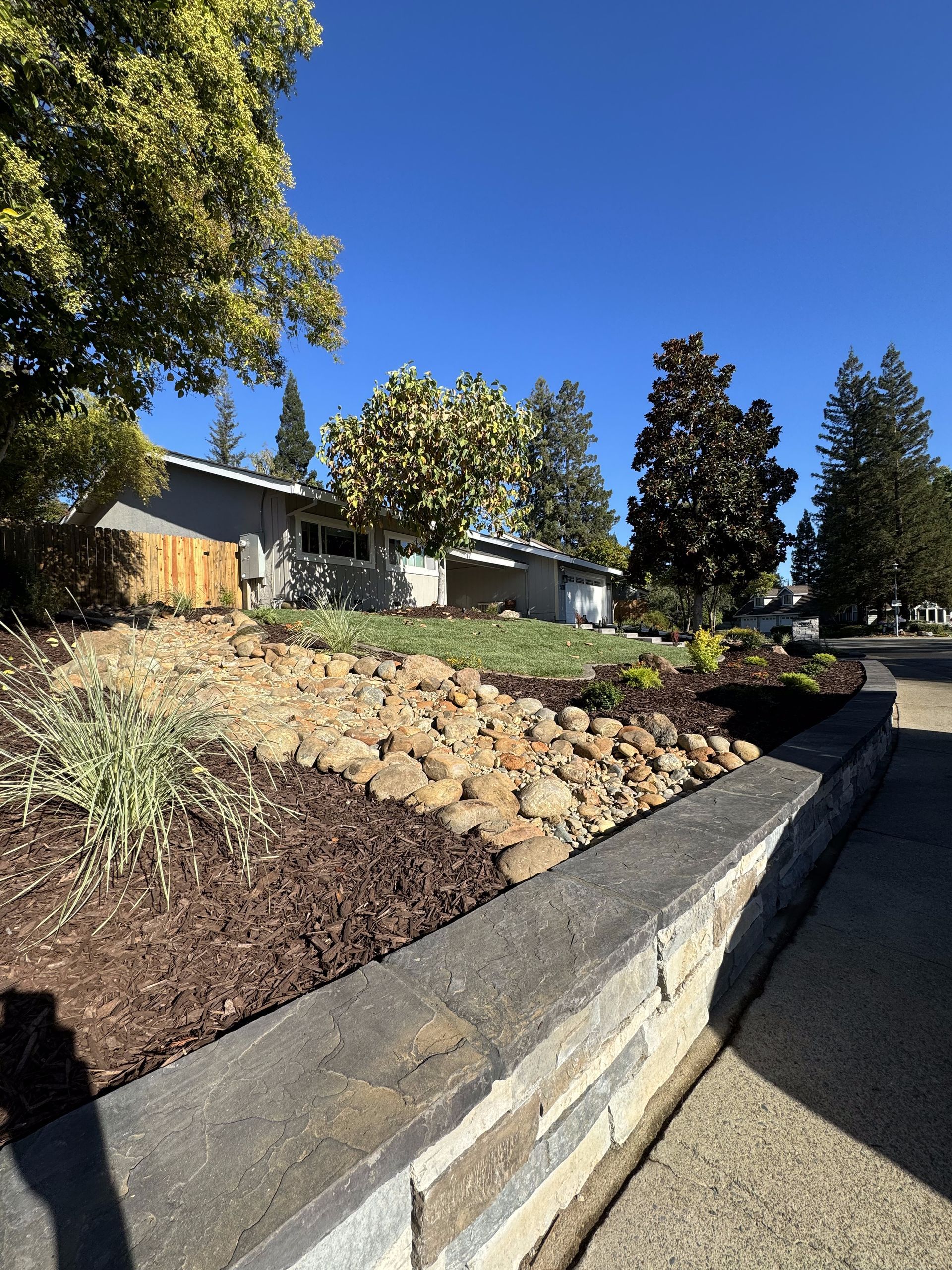 A house is sitting on top of a hill next to a stone wall.