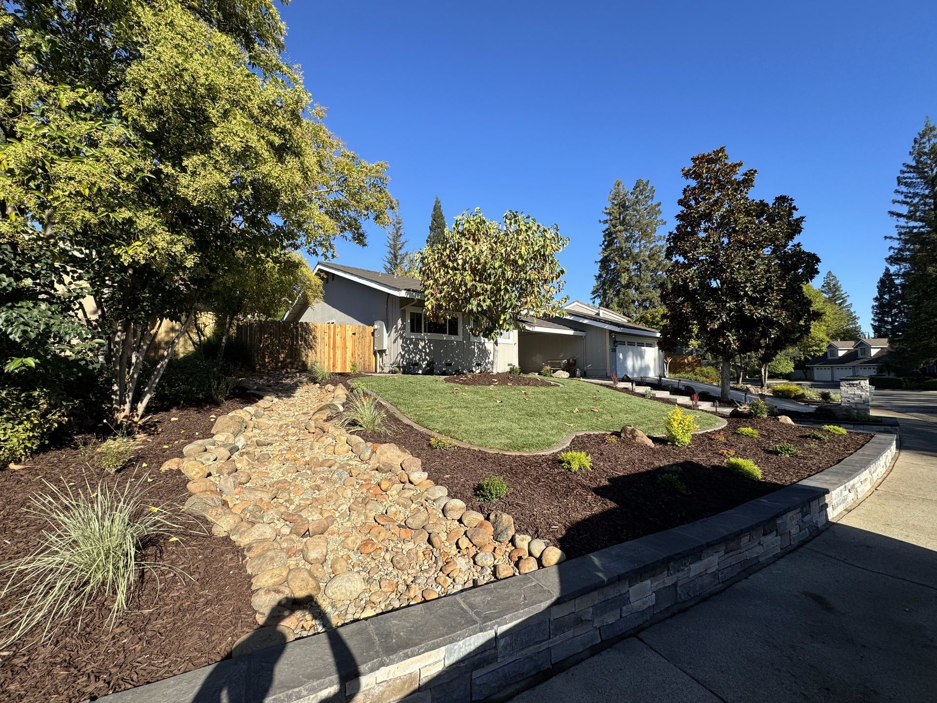 A shadow of a person is cast on the sidewalk in front of a house.