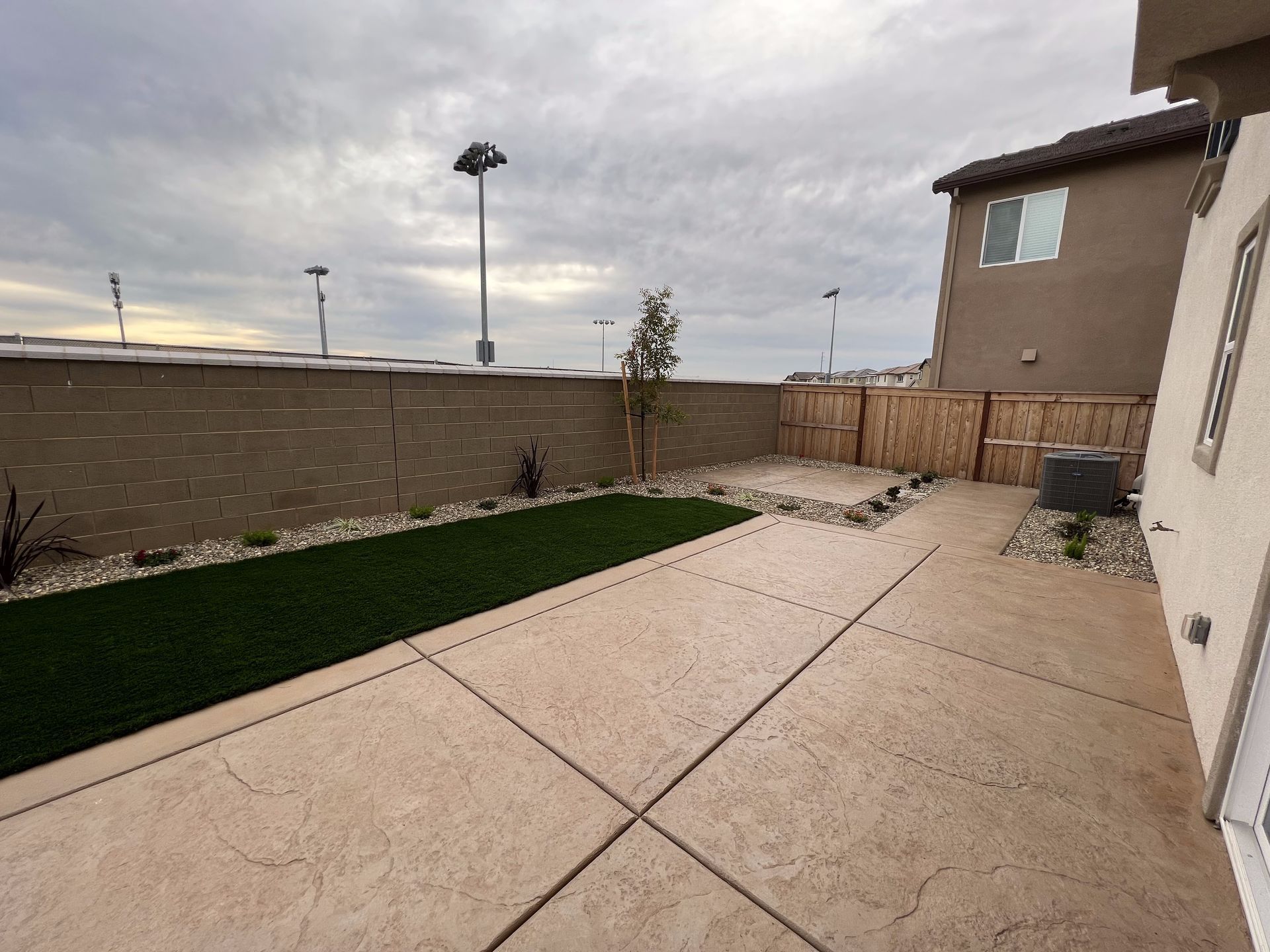 A backyard with a concrete patio and a fence