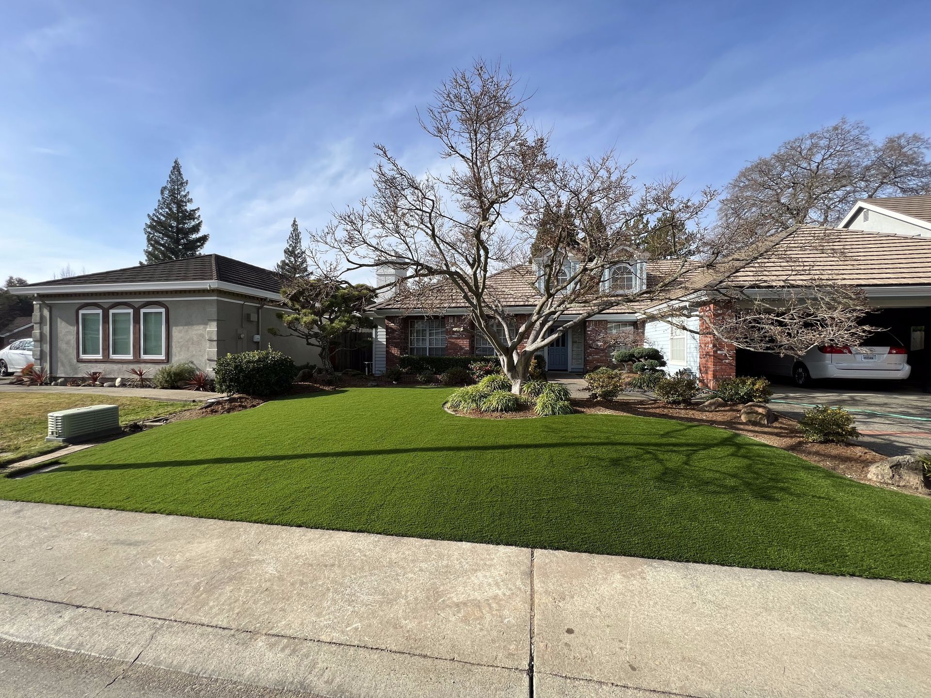 A house with a lush green lawn and a car parked in front of it
