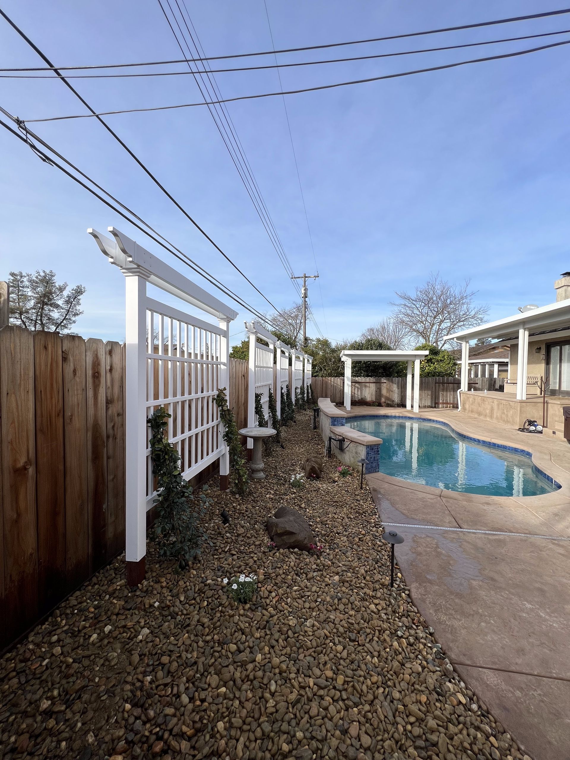 A backyard with a swimming pool and a wooden fence