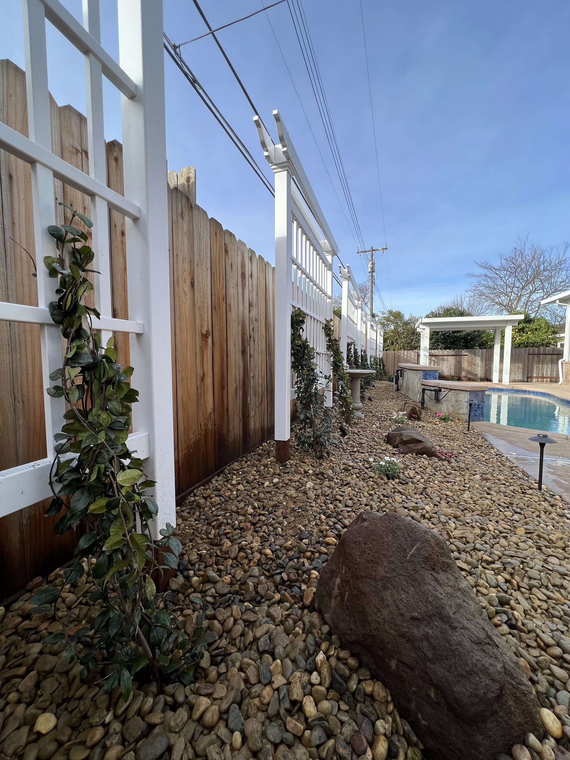A backyard with a wooden fence and a swimming pool