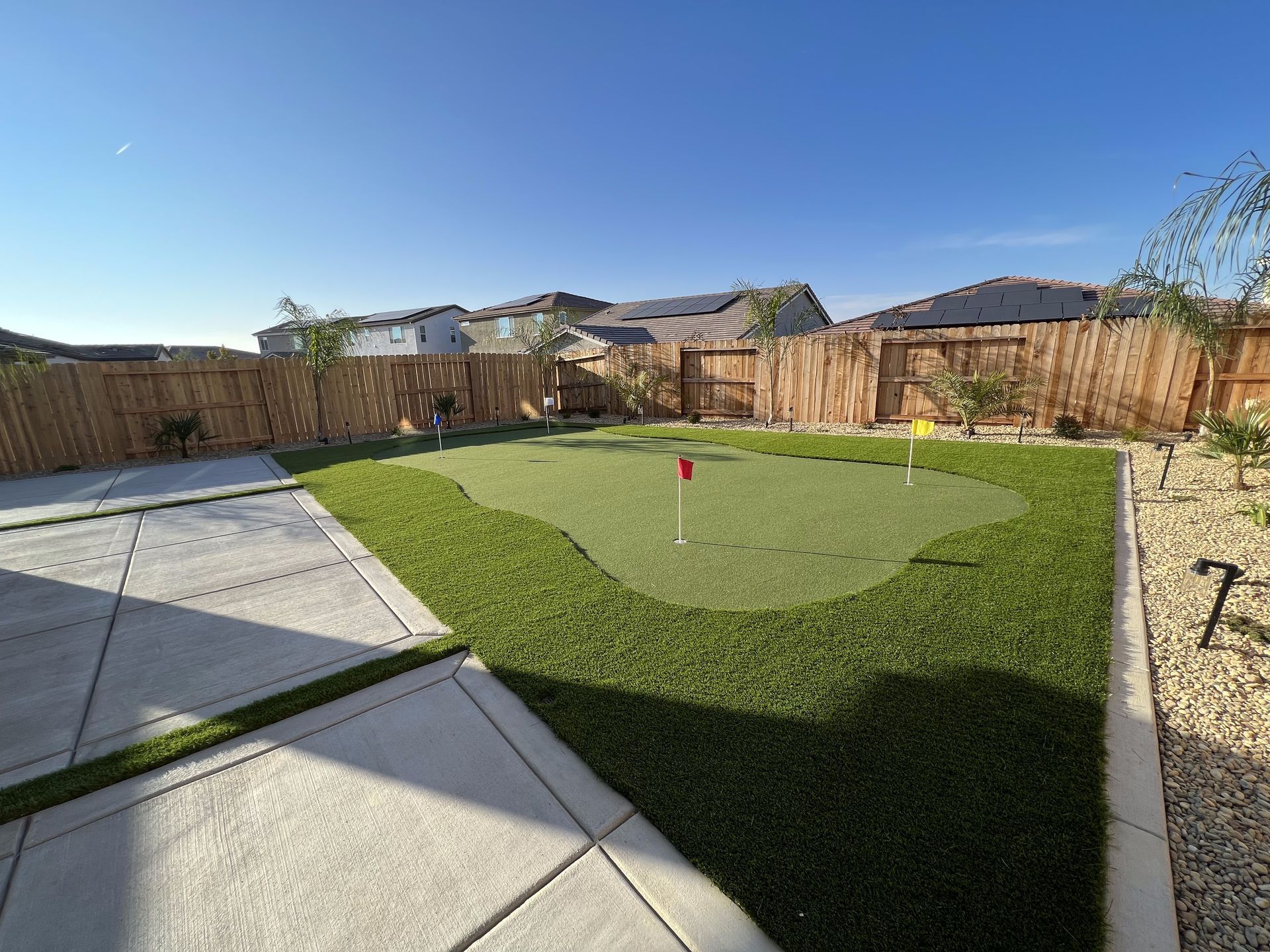 There is a putting green in the backyard of a house.