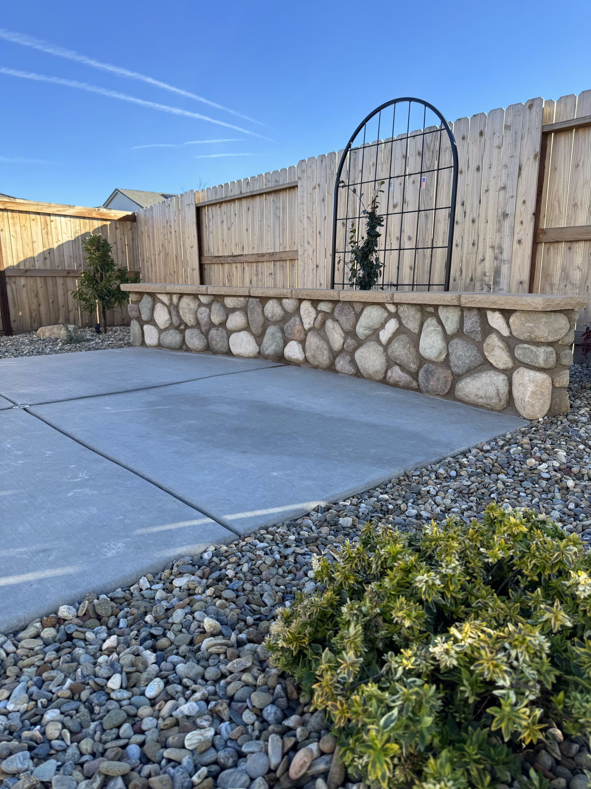 A stone wall with a wooden fence in the background
