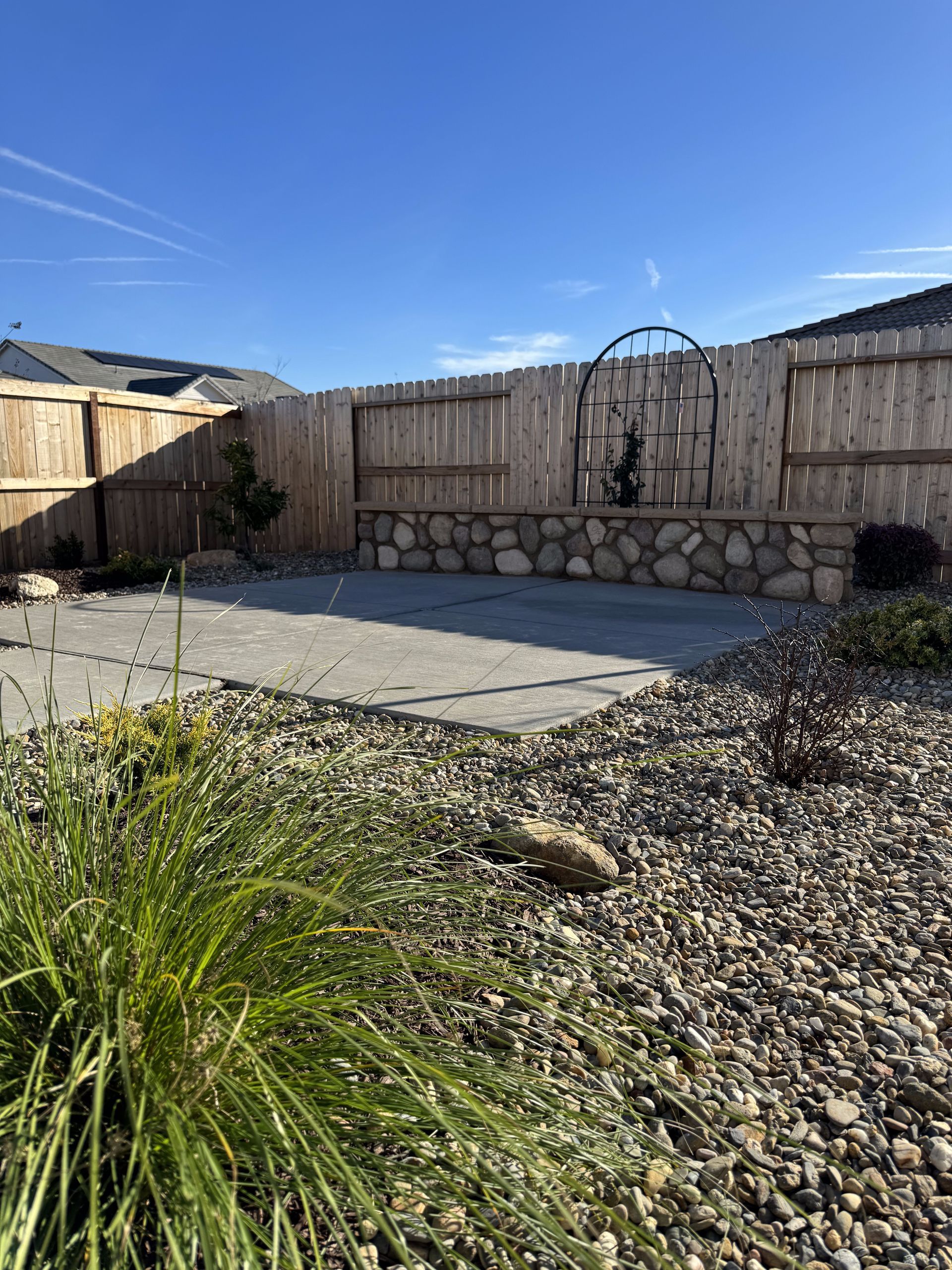 A backyard with a wooden fence and a stone wall.